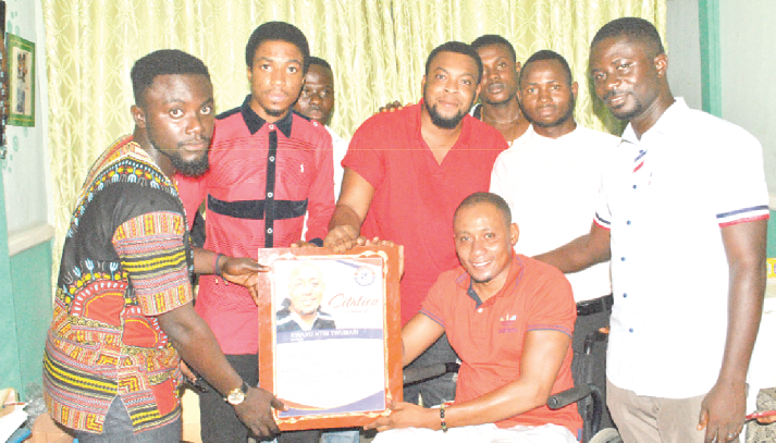  Mr Twumasi (in wheelchair) receiving the citation from Boadi-Tuffour (TESCON branch President), while Henry Duah, the Constituency Youth Organiser (first from right), and other members of the party look on